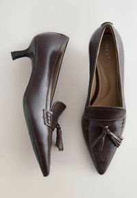 Braune Leder-Pumps mit spitzem Zehenbereich, kleinem Absatz, Quasten-Detail und dekorativer Stickerei auf dem Vorderfuß. Glatte Textur.
