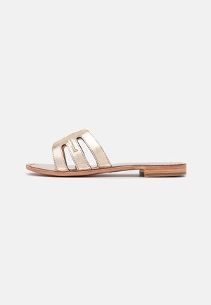 Sandalia deslizante metálica dorada con tres correas recortadas, suela plana de madera y parte superior de cuero suave. Diseño simple y estructura minimalista.