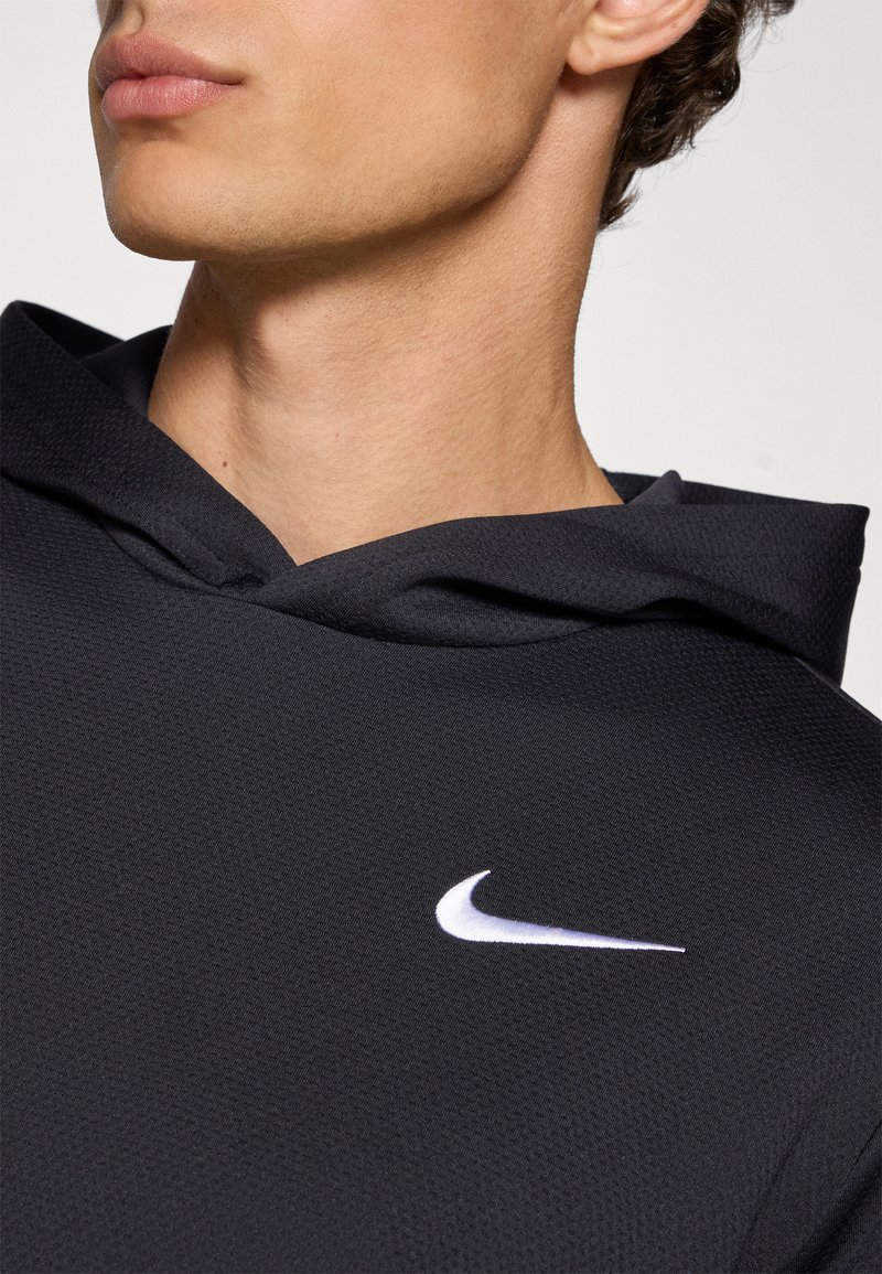 Black Nike hoodie with a textured fabric, featuring a white logo on the chest and a drawstring hood in a relaxed fit design.