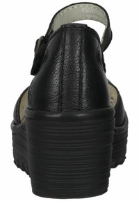 Black leather sandal with a rounded toe, adjustable strap, and a chunky textured heel. Features stitching detail and open back design.