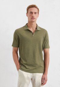 Kurzarm-Polohemd in Olivgrün, aus weichem Stoff, mit klassischem Kragen und lässigem Schnitt. Glatte Textur, minimalistisches Design.