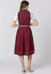 Burgundy dress with white polka dots, fitted bodice, pleated skirt, green waist belt, and white blouse with lace trim.