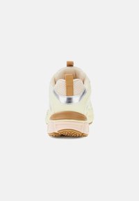 Zapatillas con una parte superior de un beige cremoso, textura de malla, acento reflectante en plata en el talón y una suela resistente en marrón claro y rosa.