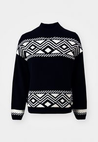 Svart tröja med åtsittande polokrage, prydd med geometriska vita mönster och ränder. Mjuk textur, långa ärmar samt ribbat avslut och muddar.