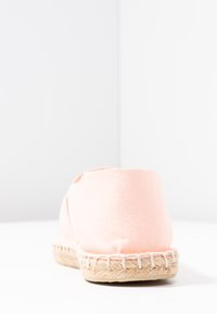 Pink canvas espadrille with a patterned jute sole and stitched accents. Features a rounded shape and a minimalistic design.