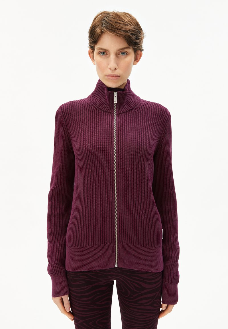 Lila gerippter Strick-Zipper-Pullover mit hohem Kragen und langen Ärmeln, ausgestattet mit einem silbernen Reißverschluss und einer körpernahen Passform.