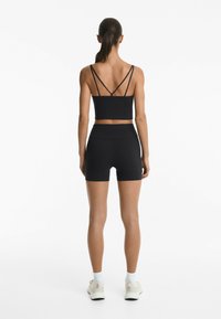 Black athletic crop top with thin straps paired with matching high-waisted shorts. Smooth, stretch fabric with a fitted design.
