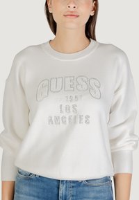 Witte sweatshirt van zacht materiaal met metallic rhinestone letters "GUESS EST. 1981 LOS ANGELES" in een relaxte pasvorm.
