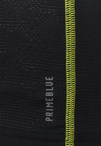 Tissu noir texturé étiqueté « PRIMEBLUE » avec une couture en zigzag verticale jaune néon sur le côté droit.