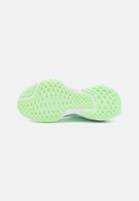 Semelle de chaussure avec une surface texturée vert clair présentant des motifs rectangulaires et carrés sur une base blanche, vue par le dessous.
