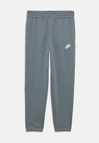 Γκρίζες φόρμες Nike με ελαστική μέση, σφιχτή μανσέτα, πλαϊνές τσέπες και λευκό λογότυπο στο αριστερό σκέλος. Λείο ύφασμα.