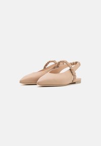 Ballerines beiges à talon ouvert avec un bout pointu et une sangle froncée au niveau du talon. Fabriquées en matériau lisse avec une semelle plate.