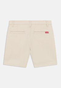 Short beige en mélange de coton, doté d'une coupe droite, de deux poches arrière et d'un petit patch logo Levi's rouge.