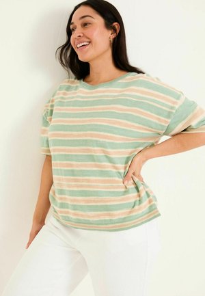 Green and beige striped oversized sweater, featuring short sleeves and a ribbed neckline. Worn with white pants, smooth texture.