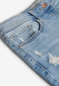 Light blue denim boy shorts with frayed edges, a small front pocket, and silver hardware. Features soft texture and faded wash detail.