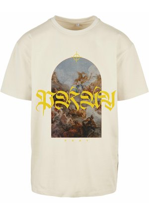 Beige bomulds t-shirt med et stort trykt grafik af en religiøs scene inden for en bue, åbnet med gul "Pray" tekst nedenunder.