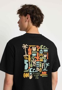 Camiseta de algodón negra con un diseño geométrico y abstracto multicolor en la parte posterior. Cuello redondo sencillo y mangas cortas.