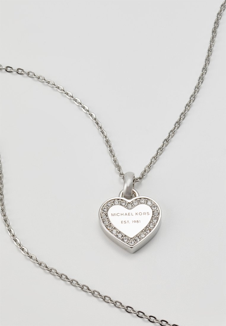 Silberner Herzanhänger mit Kristallakzenten, graviert mit "MICHAEL KORS EST. 1981", befestigt an einer zarten Kette.