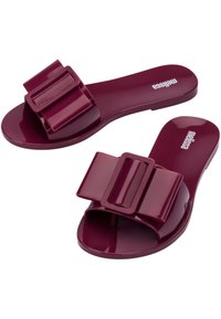 Sandali in mauve con finitura lucida, caratterizzati da un grande accento a fiocco doppio, suola piatta e design con punta arrotondata. Branding visibile sulla soletta.
