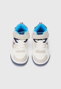 Tenis altos brancos com interior azul, detalhes cinzentos e sola azul escura. Apresenta uma faixa de Velcro e um detalhe gráfico do Mickey Mouse.
