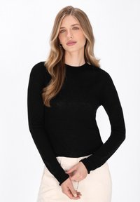 Zwarte longsleeve shirt gemaakt van een lichtgewicht materiaal, met een ronde halslijn en aansluitende mouwen, gedragen met lichtgekleurde broeken.