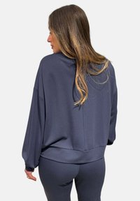 Felpa oversized di un blu navy scuro, con vestibilità comoda, orlo a costine e spalle scese, realizzata in un morbido tessuto testurizzato.