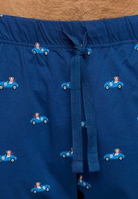 Blaue Baumwollshorts mit einem Kordelzugverschluss. Muster von Cartoon-Hunden in blauen Autos mit roten Schals, die überall aufgedruckt sind. Sanfte Textur.