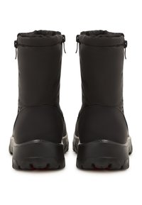 Pari av black insulated talvikengistä paksuilla pohjilla ja vetonauhoilla, nähtynä takaa valkoista taustaa vasten.