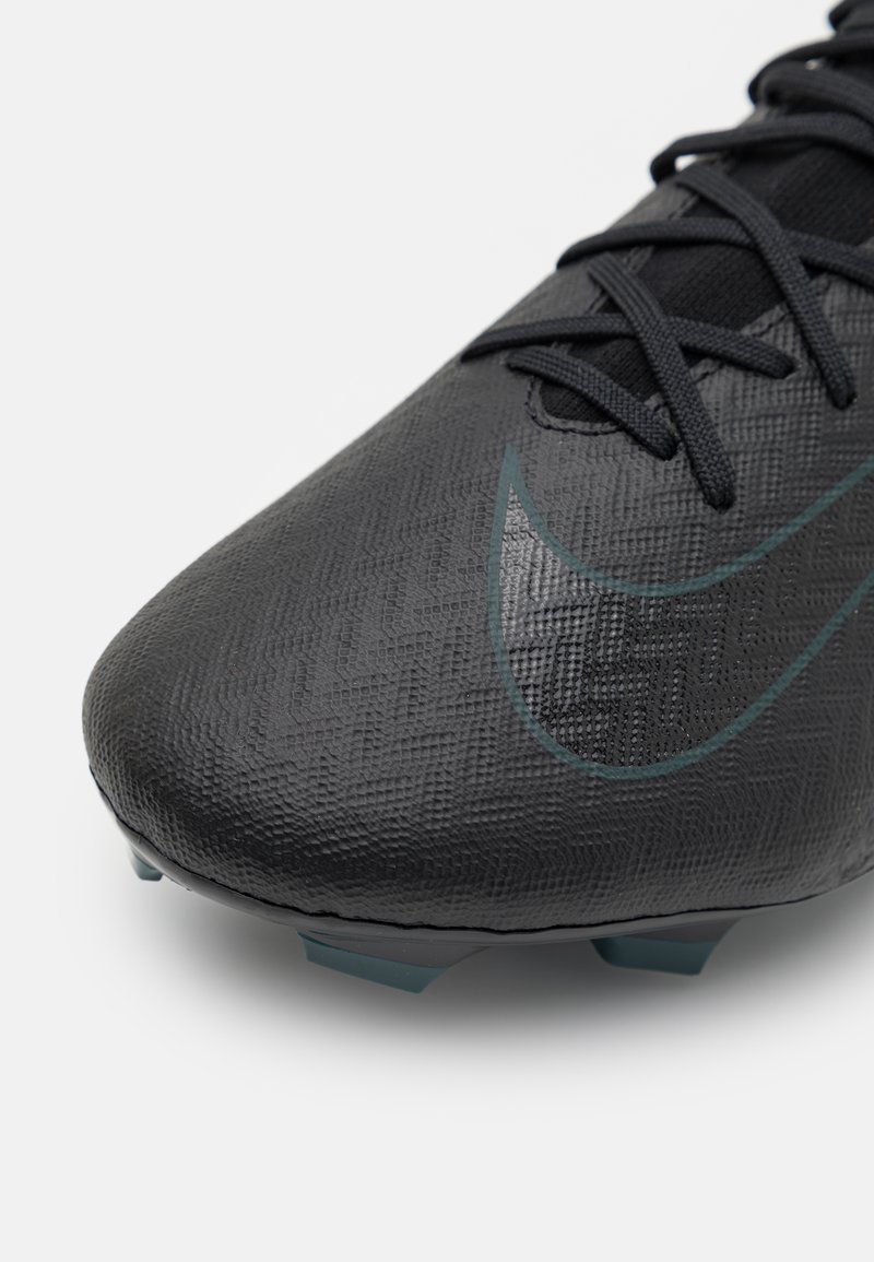 Scarpa da calcio nera con superficie texturizzata, caratterizzata da un logo Nike prominente di colore verde scuro e da una forma elegante progettata per le prestazioni.