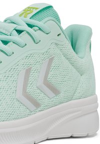 Ljus mintgrön träningssko med mesh-överkropp, texturerad design, vit sula och silverfärgade logotypdetaljer. Har vadderad krage och snörning.
