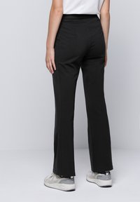 Pantalons noirs ajustés avec un design à jambes droites, en tissu lisse. Présentent une taille mi-haute et des détails de couture subtils.