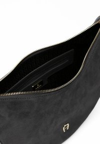 Borsa a mano in suede nero con cerniera tono oro e logo marchiato. Interno con fodera decorata e tasca a fessura per organizzazione.