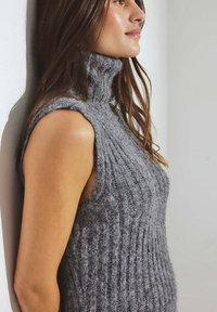 Maglione senza maniche grigio a collo alto in maglia, con texture a coste verticali e finitura morbida, caratterizzato da un design aderente e colletto arrotolato.