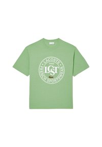 Camiseta de algodón verde claro con mangas cortas y cuello redondo, con un logotipo circular blanco que dice "LACOSTE PARIS FRENCH SPORTSWEAR."