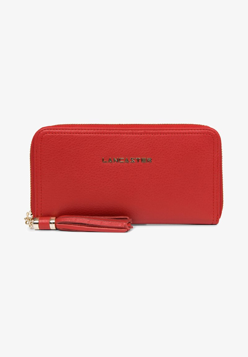 Portefeuille en cuir rouge avec fermeture éclair, logo en relief "LANCASTER" et une frange décorative. Texture lisse avec bords cousus.
