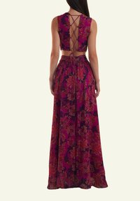 Long-flowing purple maxi dress with floral patterns, sleeveless design, open back with crisscross ties, and a fitted waistband.