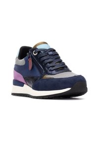 Zapatilla que presenta una mezcla de materiales: ante azul marino, malla y acentos sintéticos. El diseño incluye un tacón morado, detalles plateados y azules, y una suela texturizada.