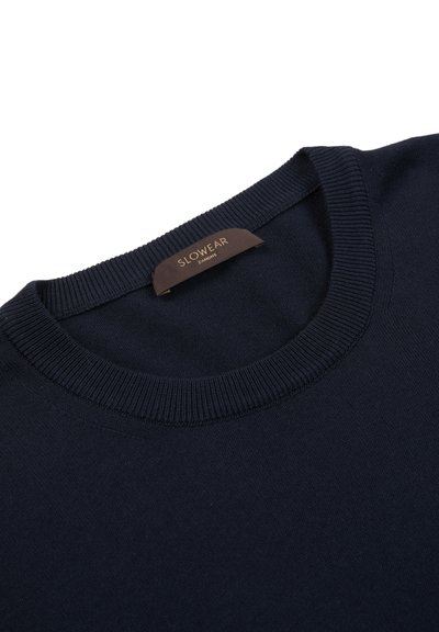 Navy blue knit sweater with a ribbed round neck; features a brown label stitched at the collar. Soft texture, clean design, and no patterns.
