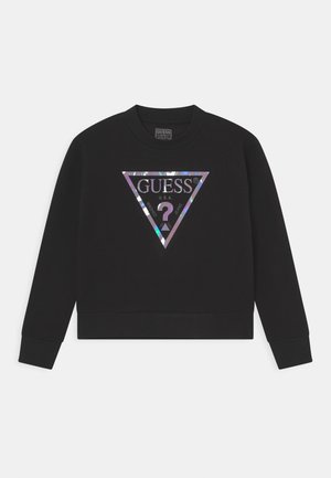 Sweatshirt noir avec un logo "GUESS" triangulaire et irisé au centre. Poignets et ourlet côtelés, avec un col ras du cou classique.