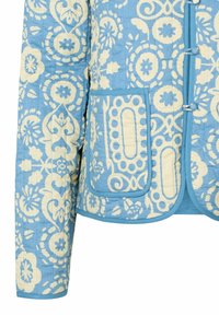 Giacca trapuntata in tessuto blu chiaro con motivi floreali bianchi. Presenta bottoni, un colletto e due tasche frontali con bordi arrotondati.