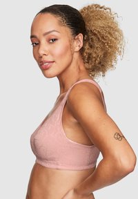 Ljusrosa sömlös bralette med blommönster, justerbara band och mjuk textur. Har en bred kant för stöd.