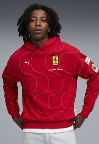 Rode hoodie van katoen met een golvend gestikt ontwerp. Voorzien van het Ferrari-logo en de tekst Scuderia Ferrari op de voorkant.