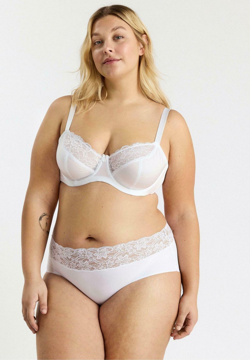 Witte kanten bh en bijpassende slip. De bh heeft verstelbare bandjes en florale kanten details; de slip heeft een kanten tailleband. Gladde stoftextuur.