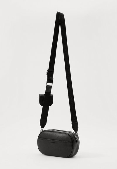 Černá texturovaná kožená crossbody taška se zipovým uzávěrem, nastavitelným nylonovým popruhem s raženým textem a malou příslušenstvím připojenou.