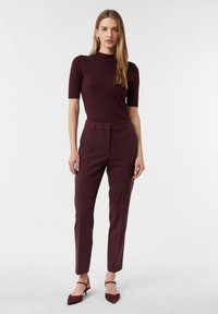 Burgundowa dopasowana bluzka z krótkim rękawem w połączeniu z pasującymi zwężającymi się spodniami. Czubate szpilki dopełniają całość. Gładka tekstura i elegancki design.