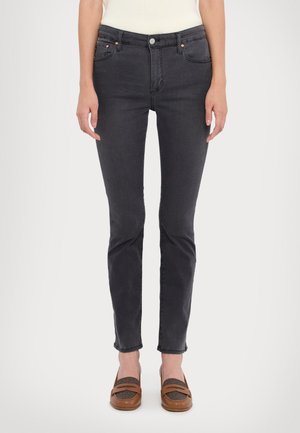 Dark gray skinny jeans with a smooth texture, five-pocket design, and subtle copper accents on the hardware. Styled with brown flat shoes.