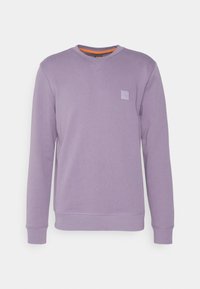 Sweat-shirt à manches longues violet clair, col rond, poignets et ourlet côtelés, avec un petit écusson carré sur la poitrine gauche.