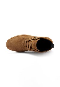 Botas de tobillo de ante color cuero con puntera redonda, cierre de cordones en la parte delantera y un pequeño lazo en la parte trasera. Textura suave y detalles cosidos alrededor de la parte superior.
