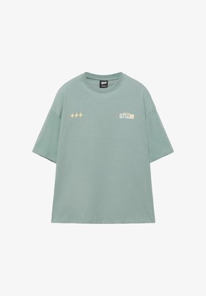 Világoszöld, túlméretezett rövid ujjú póló, bal mellrészen három sárga csillag alakzat, jobb mellrészen fehér "STWD" logó.