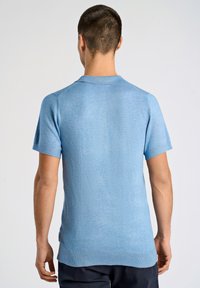 Koszulka polo z krótkim rękawem w jasnoniebieskim kolorze, wykonana z dzianiny, z prążkowanym kołnierzem i mankietem. Materiał ma gładką fakturę i luźny krój.